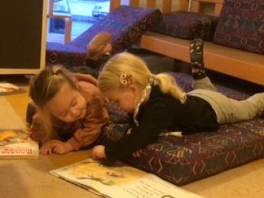 To børn ligger på gulvet og læser 